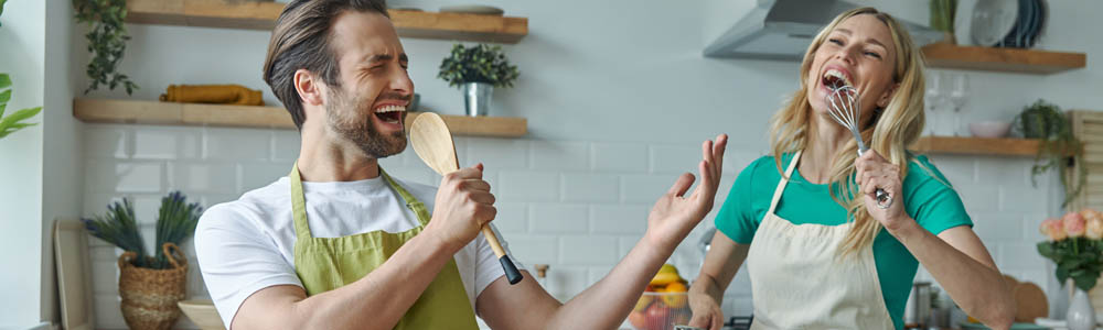 Young white couple laughing and playing in the kitchen, cooking